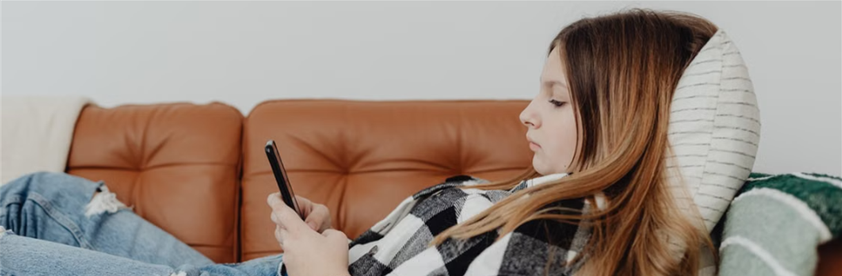 Jonge vrouw liggend op bankmet telefoon in hand