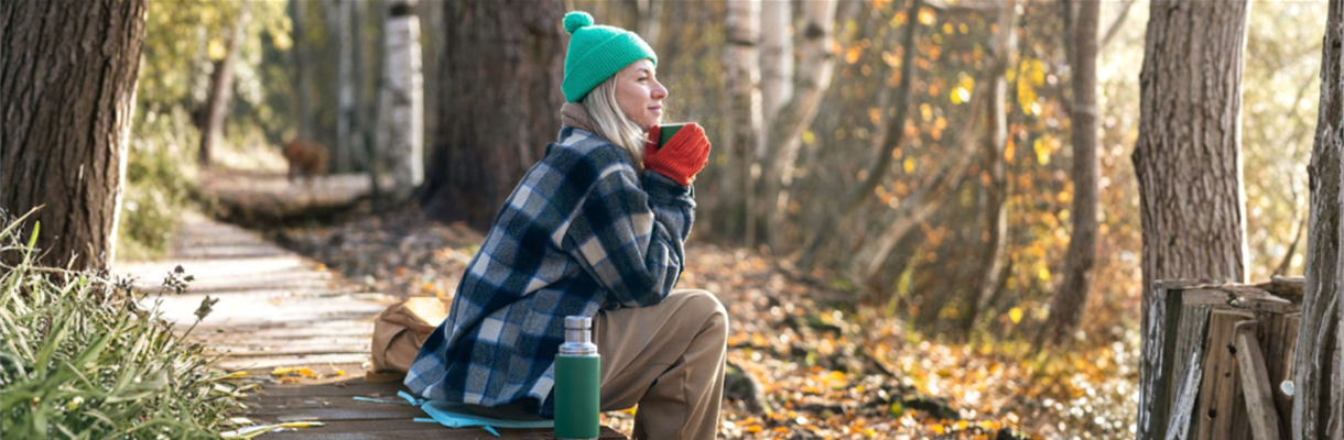 Vrouw geniet van de winterzon in het bos