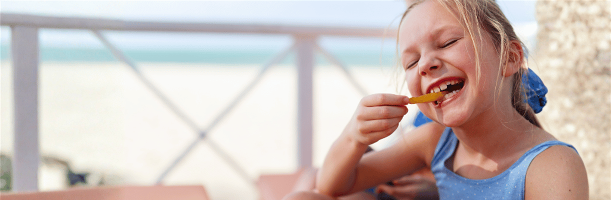 Meisje eet patat op het strand