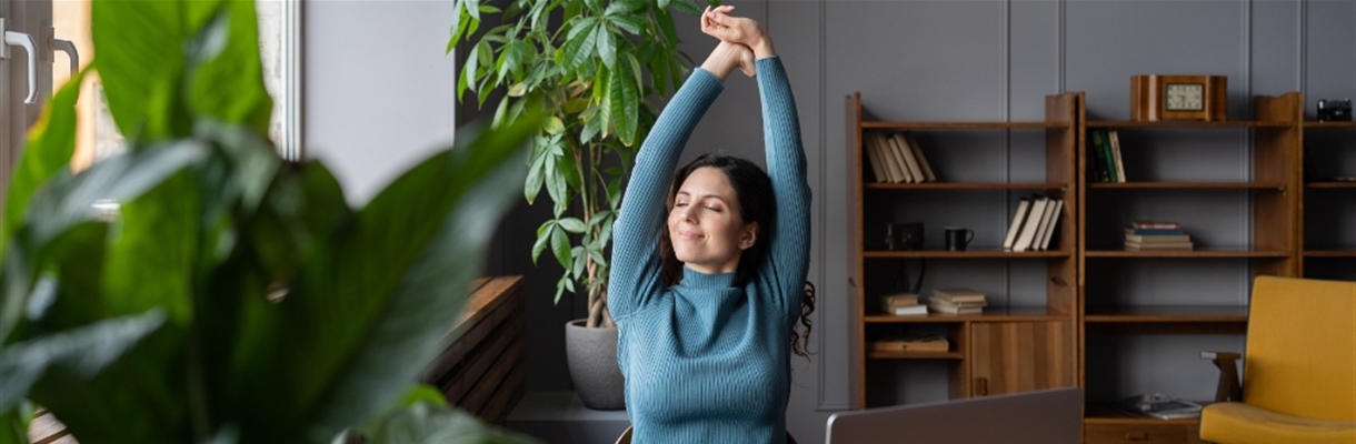 Vrouw achter bureau die zich uitrekt