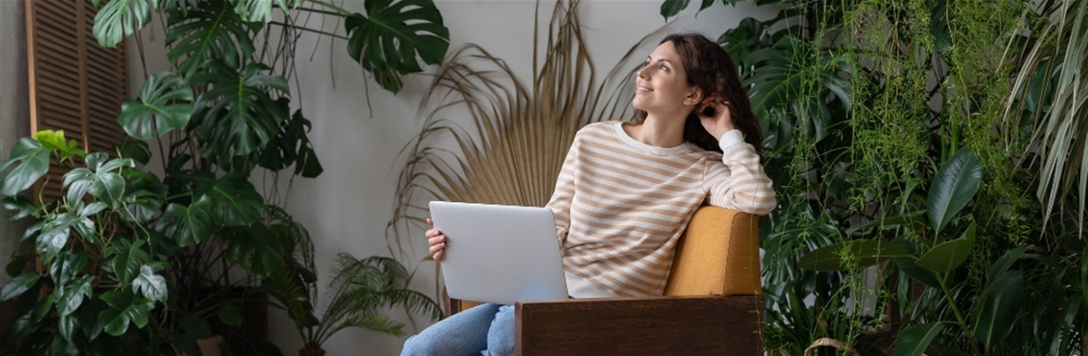 Vrouw met laptop in schoot tussen allemaal planten