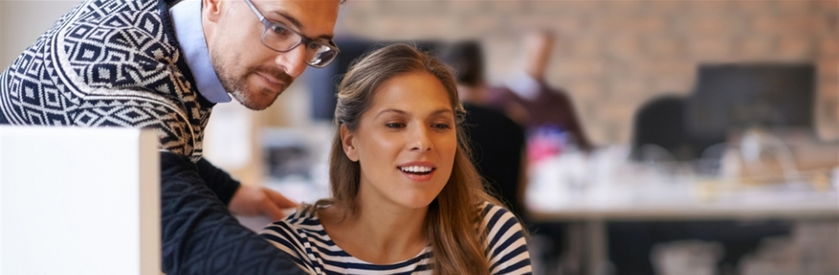 Man wijst vrouw iets aan op de laptop