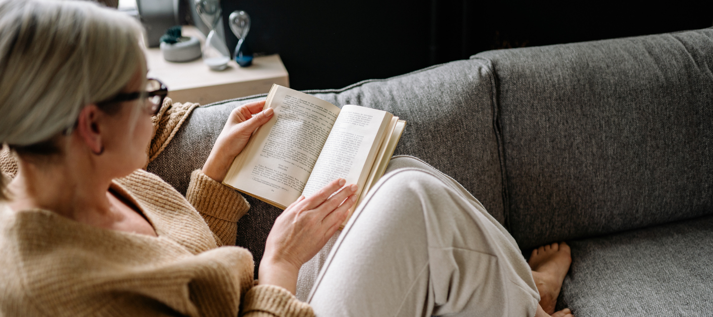 Vrouw die een boek leest op de bank